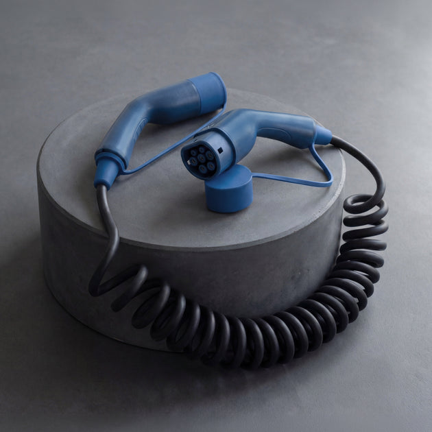 Black coiled EV charging cable with blue Type 2 ends arranged on concrete